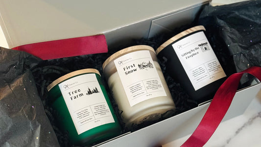 Three candles in a gift box with a visible brand label on a marble surface.